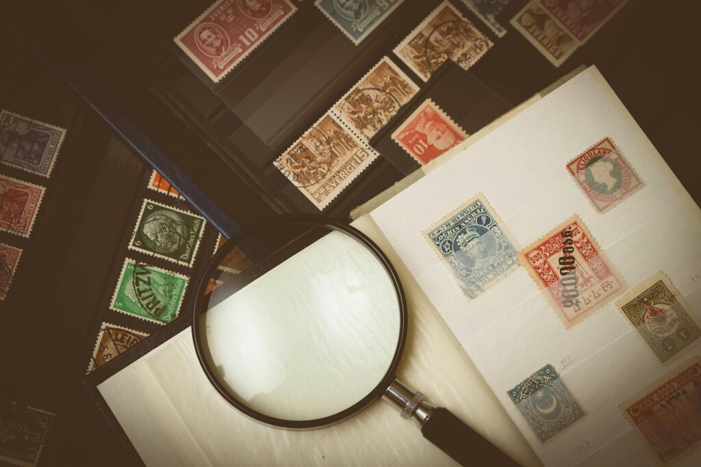 Explore a detailed view of vintage postage stamps through a magnifying glass, highlighting intricate designs.